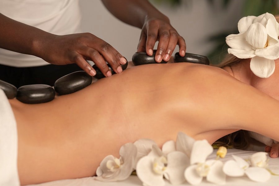 Piedras calientes sobre la espalda junto a flores blancas, ritual de spa.